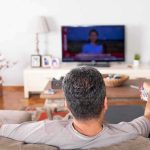 Basement Chair Horror Over a Football Game Man watching TV from couch with remote in hand