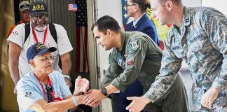 Veteran in wheelchair greeted by military personnel at event