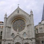 Stone church facade with large rose window and cross
