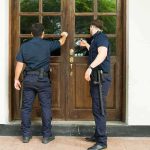 Two uniformed officers knocking on a wooden door
