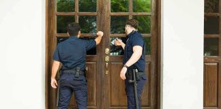 Two uniformed officers knocking on a wooden door