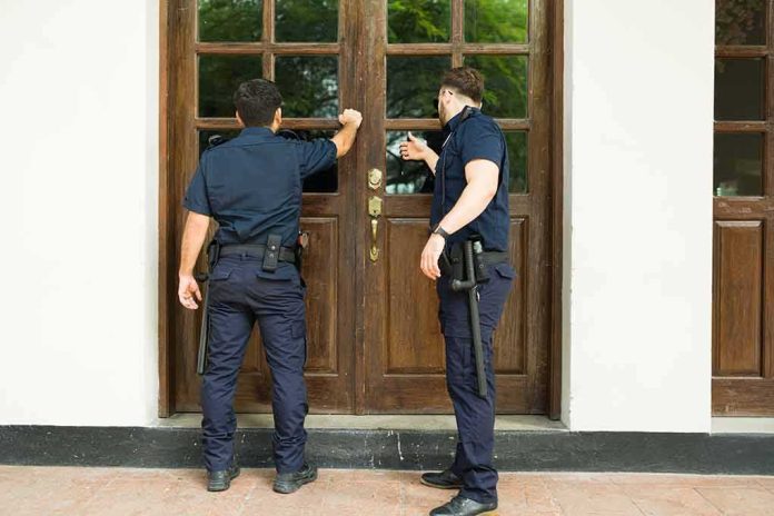 shutterstock_2201326935 Two uniformed officers knocking on a wooden door