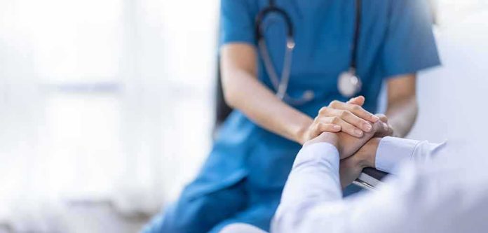 shutterstock_2219183715 Nurse comforting a patient by holding hands