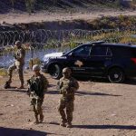 Border Calm Aftermath – Credit War Erupts Soldiers stand near barbed wire beside a police SUV