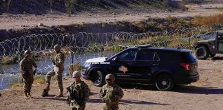 Border Calm Aftermath – Credit War Erupts Soldiers stand near barbed wire beside a police SUV