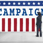 $64M Shock Upends Texas Race Man in suit writing on large campaign banner with stars and stripes
