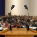 Podium with two microphones facing a blurred audience