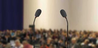 Candidate Vanishes – Flu Excuse or Damage Control? Podium with two microphones facing a blurred audience