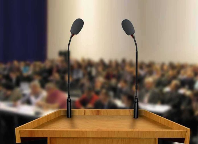 Podium with two microphones facing a blurred audience